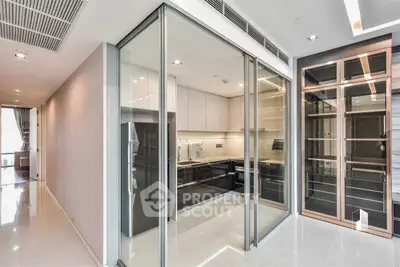 Modern kitchen with sleek glass doors and high-end appliances in luxury apartment.