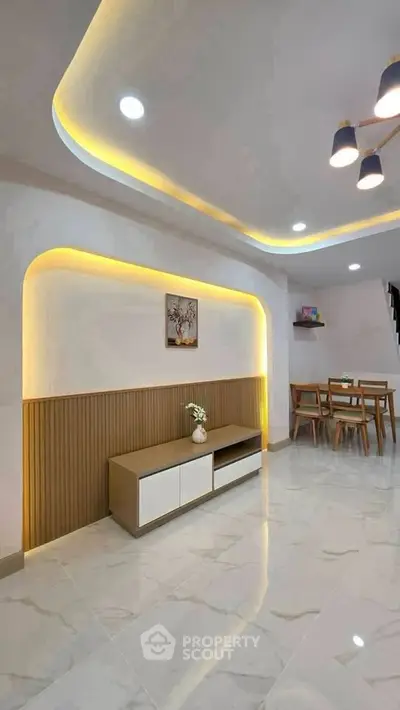 Modern living room with stylish lighting and dining area, featuring sleek furniture and elegant decor.