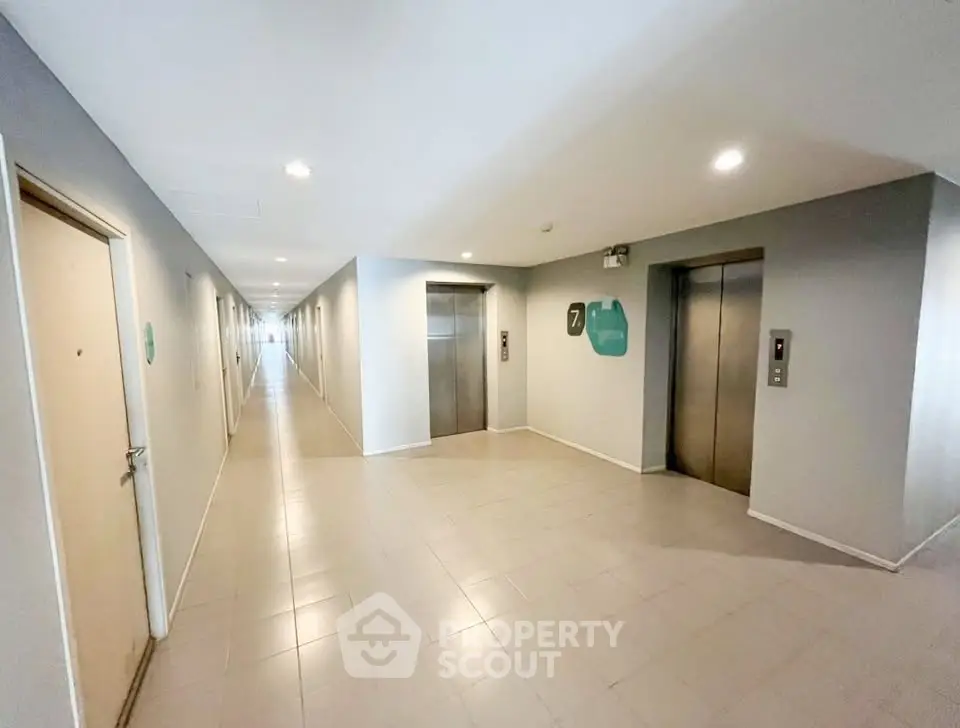Modern apartment building corridor with elevators and bright lighting.