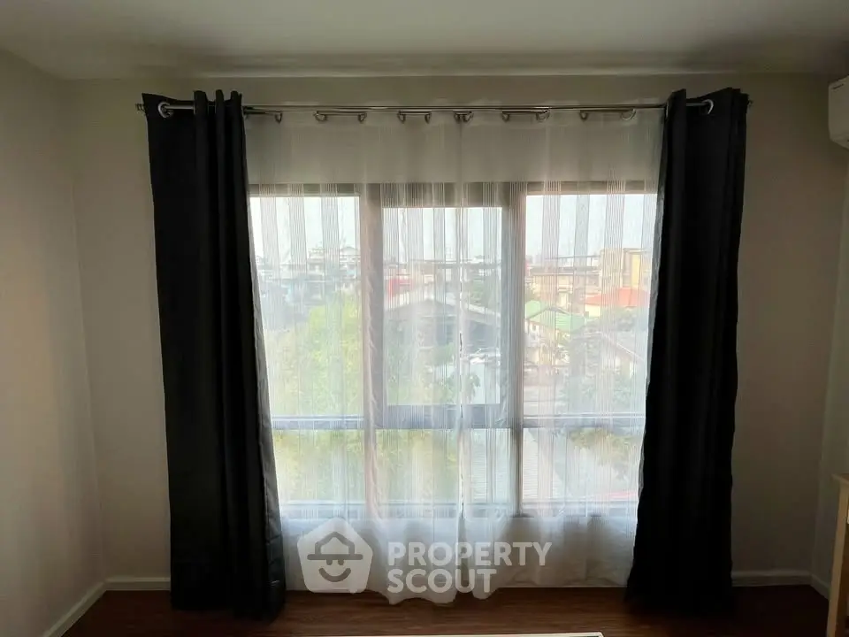 Bright room with large window and elegant curtains offering a serene view.