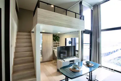 Modern loft apartment with mezzanine, large windows, and stylish dining area.