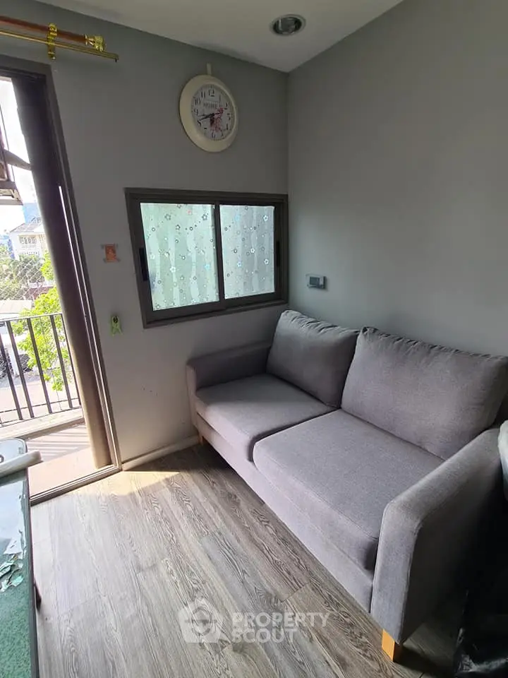 Cozy living room with modern gray sofa and balcony view, perfect for relaxation.