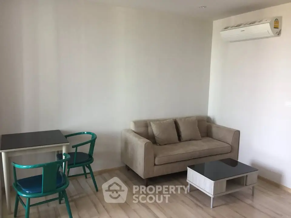 Cozy living room with modern sofa, coffee table, and dining set, featuring air conditioning.