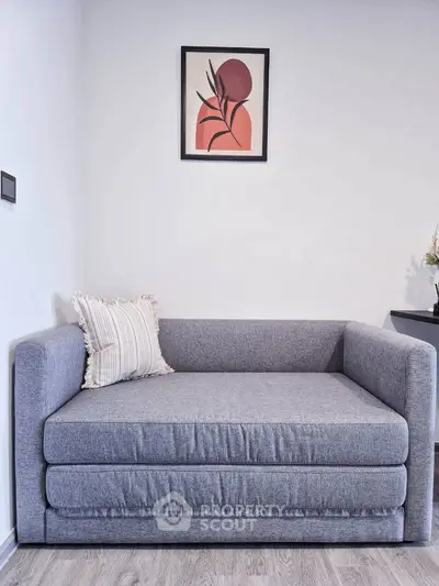 Modern living room with stylish gray sofa and abstract wall art, perfect for contemporary home decor.