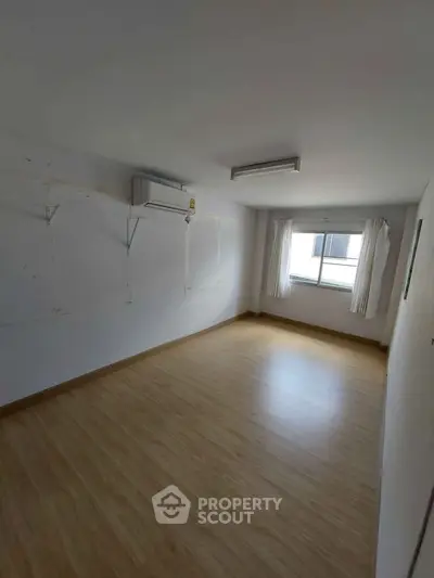 Spacious empty room with wooden flooring and air conditioning