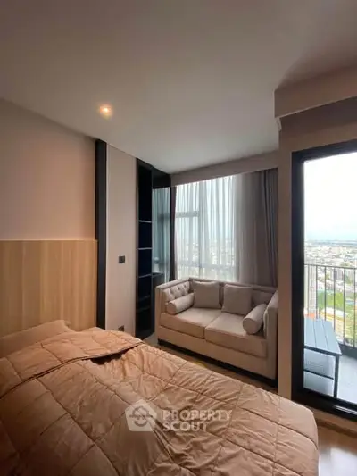 Cozy bedroom with a plush bed and sofa, featuring a large window with a stunning city view.