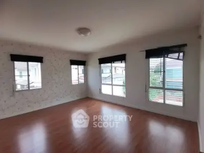 Spacious empty room with large windows and wooden flooring, perfect for customization.