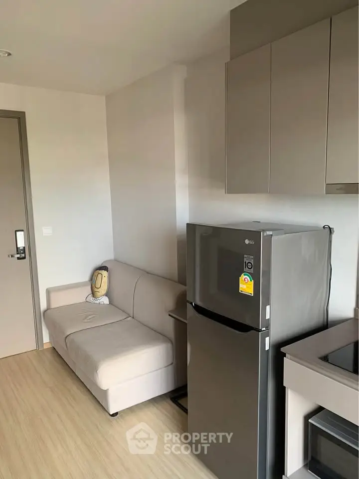 Modern kitchen with sleek fridge and cozy seating area in stylish apartment.