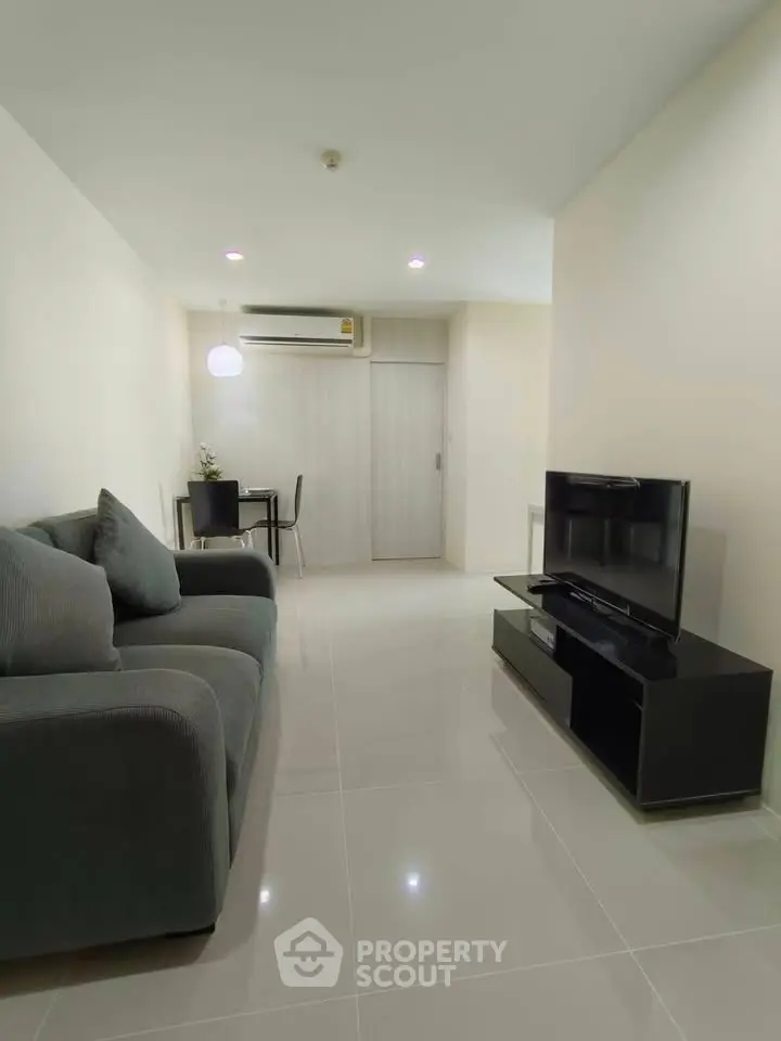 Modern living room with sleek furniture and minimalist design, featuring a cozy sofa and flat-screen TV.