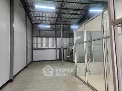 Spacious industrial warehouse with high ceilings and glass partitioned office space.