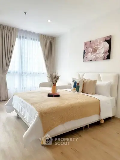 Elegant bedroom with modern decor, featuring a cozy bed, stylish artwork, and natural light from large windows.