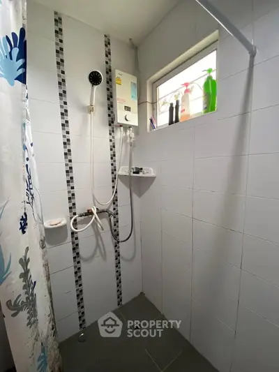 Compact bathroom with shower and window, featuring modern tiles and a shower curtain.