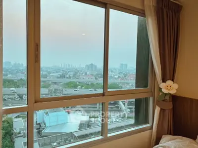 Spacious bedroom with large window offering stunning cityscape views, perfect for urban living.