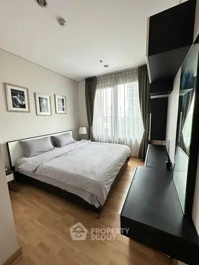 Modern bedroom with large window, stylish decor, and sleek furniture in a contemporary apartment.