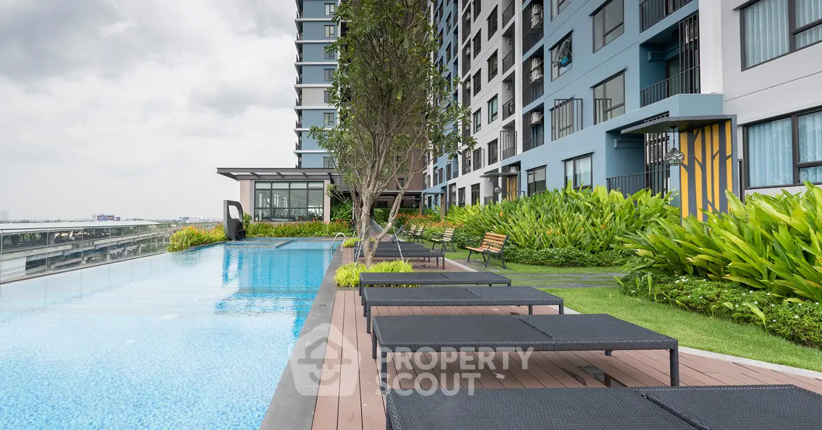 Modern apartment building with pool and lush garden area, perfect for relaxation.