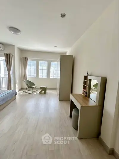 Spacious and bright bedroom with modern furnishings and large windows.