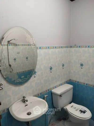 Charming bathroom with floral tile design and round mirror, perfect for a cozy home.