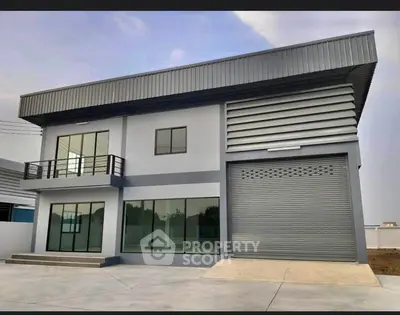 Modern industrial-style building with large windows and garage door.