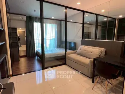 Modern studio apartment with glass partition, cozy sofa, and sleek dining area.
