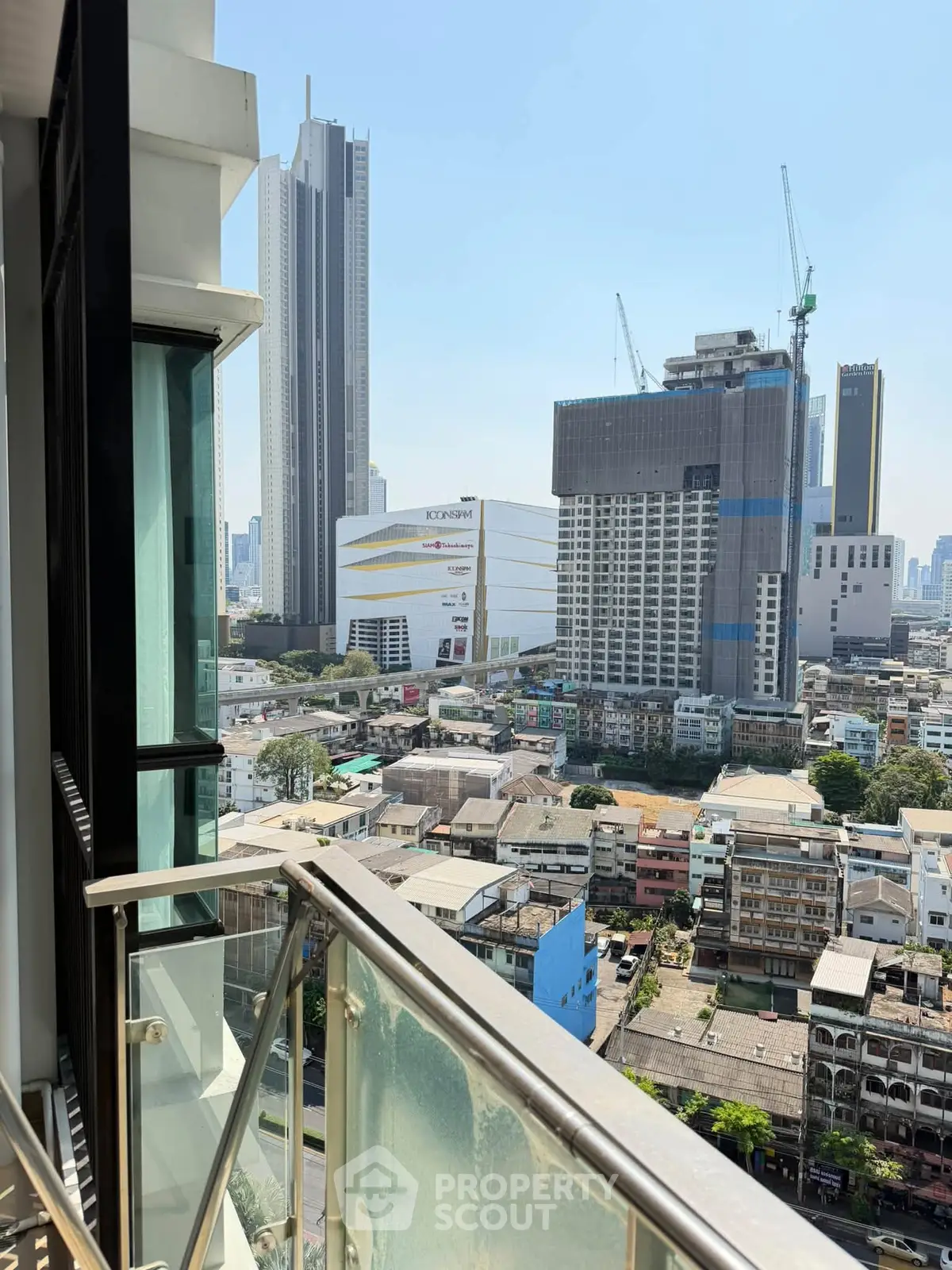 Stunning cityscape view from a modern balcony with glass railing, showcasing urban skyline and high-rise buildings.