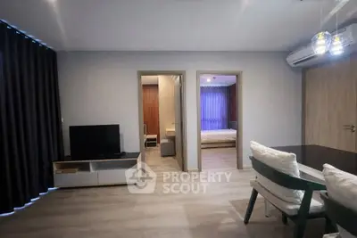 Modern living room with TV, dining area, and view into bedrooms