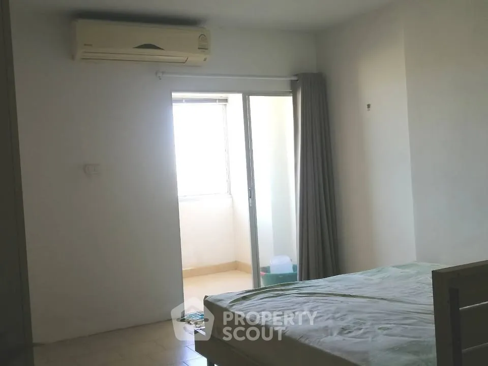 Spacious bedroom with air conditioning and balcony access for comfortable living.