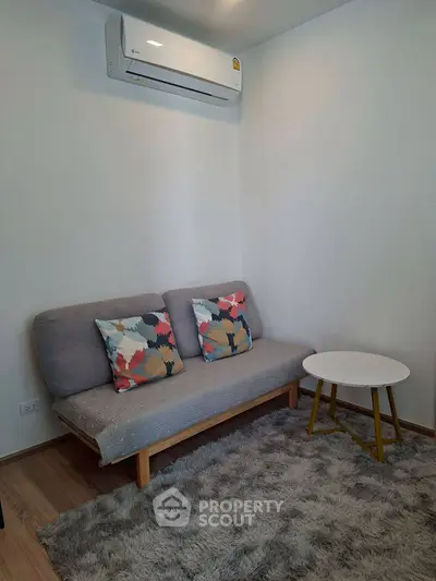Cozy living room with modern sofa, colorful cushions, and air conditioning unit.