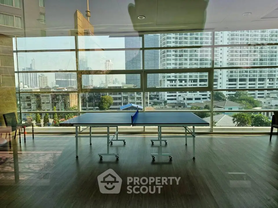 Spacious indoor recreational area with table tennis and city view, perfect for leisure and relaxation.