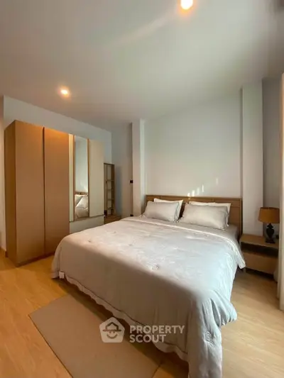 Spacious bedroom with cozy lighting and modern wooden furniture, perfect for relaxation.