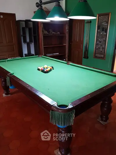 Spacious game room with classic billiard table and elegant lighting, perfect for entertainment and leisure.