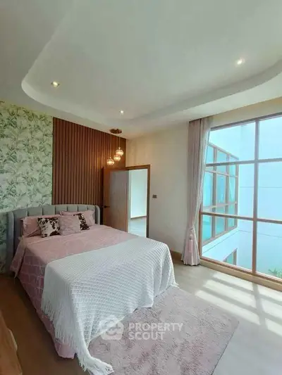 Luxurious bedroom with elegant decor and large window offering natural light