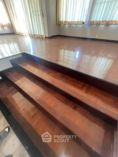 Spacious interior with polished wooden floors and elegant curtains, ideal for modern living.