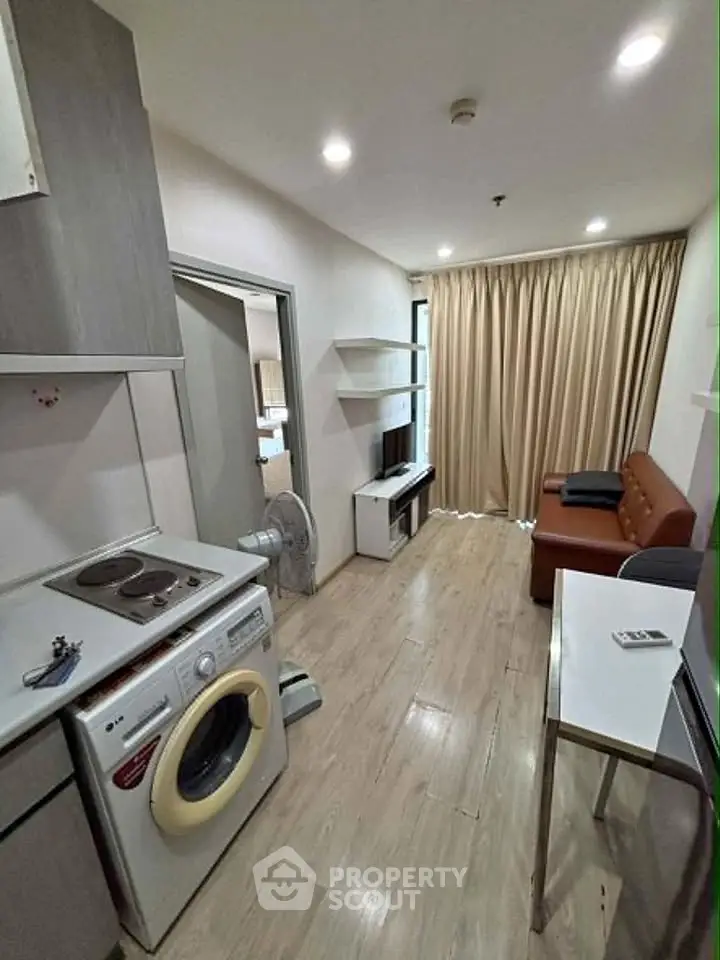 Modern compact living room with integrated kitchen and washing machine, ideal for urban living.