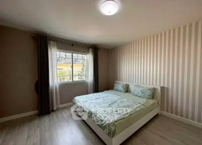 Spacious bedroom with modern decor and large window for natural light.