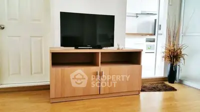 Modern living room with sleek TV stand and flat-screen TV, wooden flooring, and stylish decor.