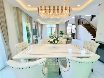 Luxurious open-plan living and dining area with elegant chandelier and plush seating in a modern home.