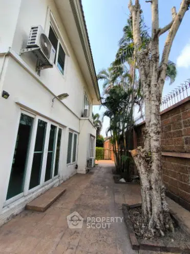 Spacious exterior view of a modern home with lush greenery and paved walkway.