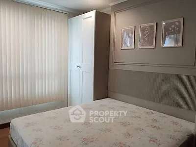 Cozy bedroom with floral bedding and elegant decor, featuring a white wardrobe and framed art on the wall.