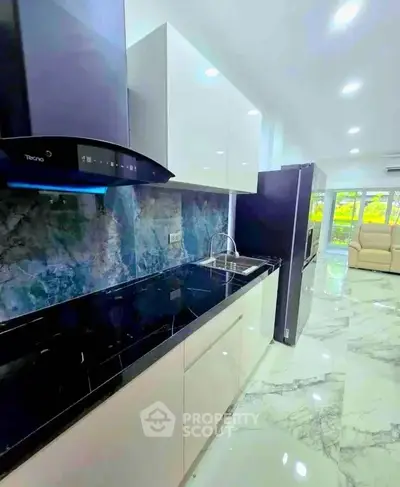 Modern kitchen with sleek design and open layout, featuring marble flooring and high-end appliances.