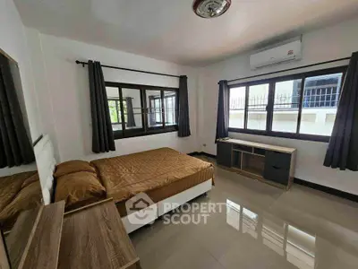 Spacious bedroom with modern furnishings and large windows for natural light.