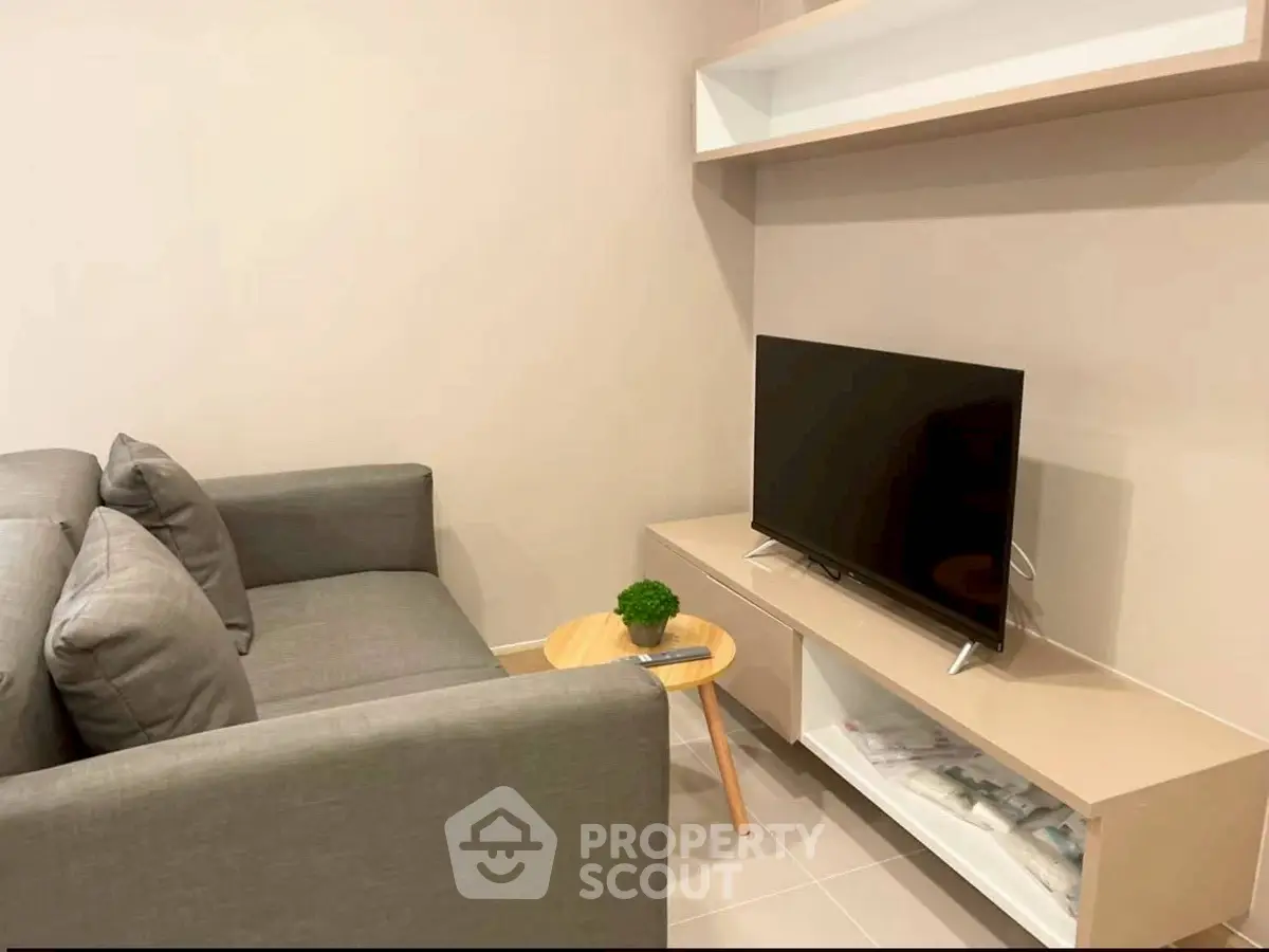 Cozy living room with modern sofa and flat-screen TV, perfect for relaxation.