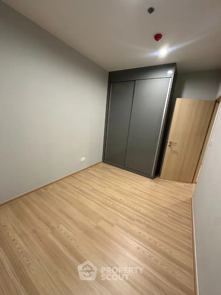 Spacious empty bedroom with wooden flooring and built-in wardrobe.