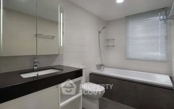 Modern bathroom with sleek design, featuring a bathtub and stylish vanity.