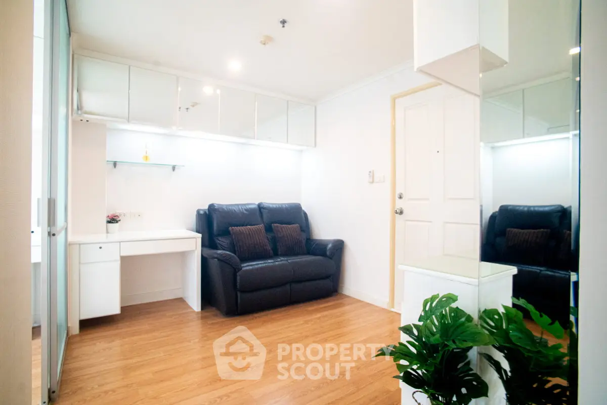 Modern living room with sleek design, featuring a black leather sofa and wooden flooring, perfect for urban living.