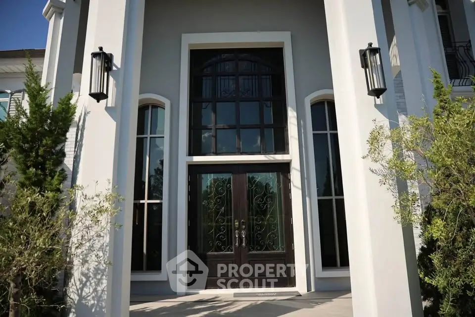 Elegant entrance of a luxury home with grand double doors and tall windows.