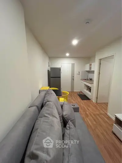 Modern living room with sleek gray sofa and compact kitchen area, perfect for urban living.