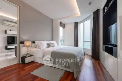 Luxurious modern bedroom with hardwood floors and large windows offering natural light.