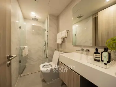 Modern bathroom with glass shower and sleek vanity in luxury apartment.