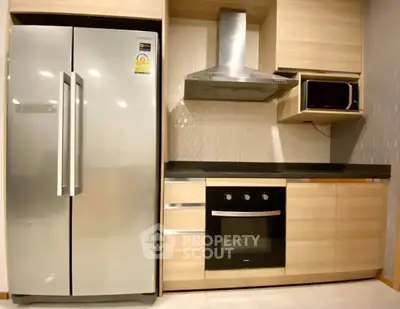 Modern kitchen with stainless steel appliances and sleek wooden cabinetry.