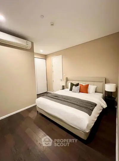 Modern bedroom with elegant decor and hardwood floors, featuring a cozy bed and ambient lighting.